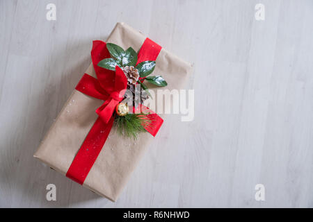 Nouvelle année objet thème isolé sur table en bois présent rouge à l'angle de vue de dessus close-up.du papier Craft boîte-cadeau à égalité avec thème de Noël ruban rouge isolé sur fond de bois.Joyeux noël Banque D'Images