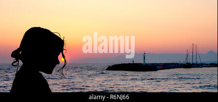 Silhouette d'une jeune fille avec coucher de soleil sur la mer à Gouves, Crète, Grèce Banque D'Images