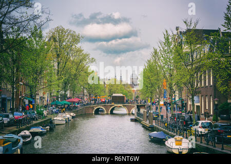 AMSTERDAM, Pays-Bas - 29 avril 2016 : Canal à Amsterdam avec ciel nuageux, l'église et arbres verts, paysage urbain Banque D'Images