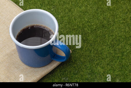 Café en gobelet bleu sur fond d'herbe. Banque D'Images