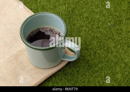 En gobelet de café vert sur fond d'herbe. Banque D'Images