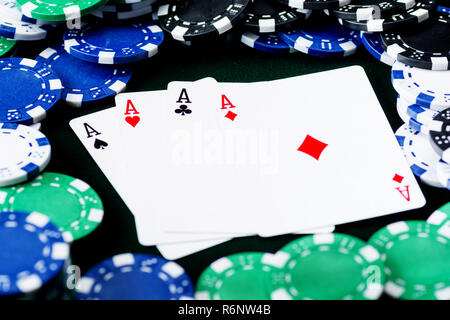 Une main de poker gagnante de quatre as combinaisons de cartes à jouer sur fond noir avec des jetons de poker Banque D'Images