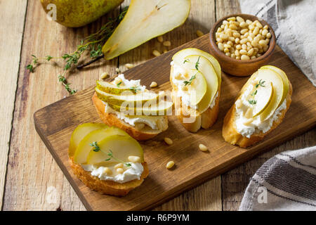 Antipasti italiens des en-cas pour le vin. Brushetta avec fromage, poire et noix de pin sur une table en bois. Banque D'Images