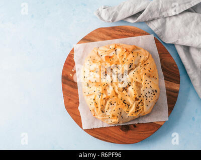 Spanakopita tarte grecque sur un papier blanc sur fond bleu. Végétarien ou vegan Spanakopita Tarte aux épinards de pâte phyllo. Copier l'espace. Des idées et recettes pour des repas santé. Vue de dessus ou de télévision. Banque D'Images