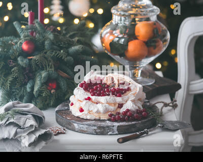 Pavlova gâteau Meringue avec de la crème fouettée et de groseille rouge sapin sur fond d'arbre de Noël. L'humeur et la photo de l'atmosphère pour les vacances d'hiver. La NOUVELLE ZELANDE Australian dessert pavlova. Copy space Banque D'Images