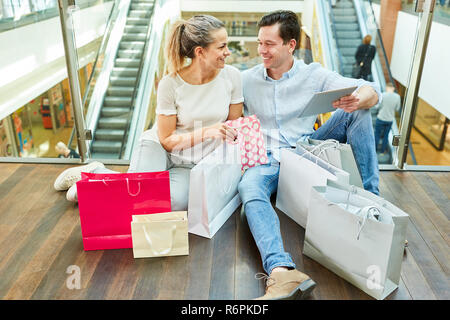 Young couple with shopping bags in shopping mall prend pause de shopping Banque D'Images