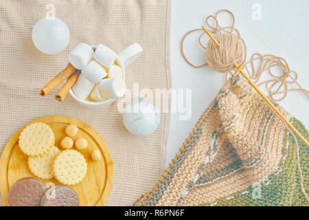 Café chaud avec les cookies, les guimauves, la cannelle, les décorations de Noël et des outils de tricot écharpe sur la table Banque D'Images