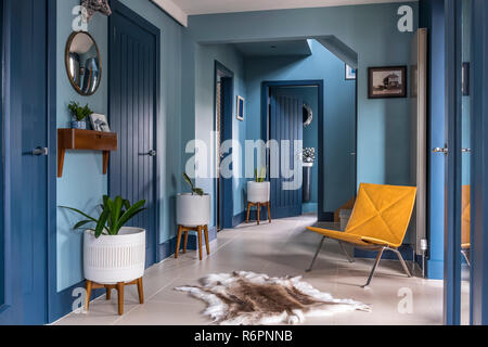 Hall entrée avec chaise jaune et bleu tapis de rennes avec des portes dans le Hampshire Mill House redessiné par peintre Emma Banque D'Images