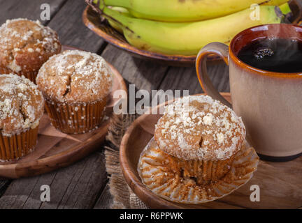 Bananes et noix muffin et tasse de café sur une plaque de bois avec des muffins et des bananes en arrière-plan Banque D'Images