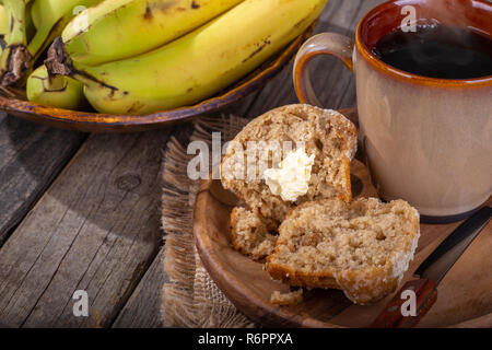 Muffins Bananes et noix coupées en deux avec une tasse de café sur une plaque de bois et un bol de bananes en arrière-plan Banque D'Images