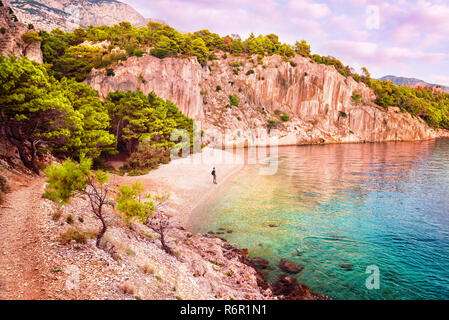 Sac à dos avec jeune homme debout sur la plage de Nugal isolée vide dans la Riviera de Makarska, Croatie après le coucher du soleil à la recherche en mer Banque D'Images