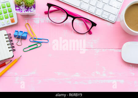 Vue de dessus de table de bureau avec espace de travail et des accessoires de bureau y compris calculatrice, clavier, souris, lunettes, clips, fleur, plume, crayon, carnet de notes, ordinateur portable et de café sur fond de bois de rose. Banque D'Images