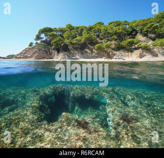 Espagne littoral méditerranéen avec une plage et un fond rocheux érodé sous l'eau avec un filet de pêche emmêlé et partagé la moitié de l'eau au-dessus et au-dessous Banque D'Images