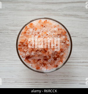 Le sel de mer de l'himalaya dans un bol en verre blanc sur fond de bois, vue du dessus. Mise à plat, d'en haut. Banque D'Images