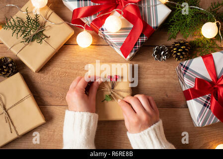 Woman's hands lier l'archet sur vintage présent sur fond rustique. Décor de fête pour les vacances d'hiver : anniversaire, Saint Valentin, Noël, Jour de l'Ye Banque D'Images