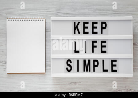 "Simplifier la vie" mots sur carte moderne, blank notepad plus de surface en bois blanc, vue de dessus. Mise à plat, d'en haut. L'espace pour le texte. Banque D'Images