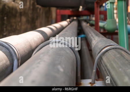 Noir et noir long tuyau d'acier à côté du mur de béton noir. Banque D'Images