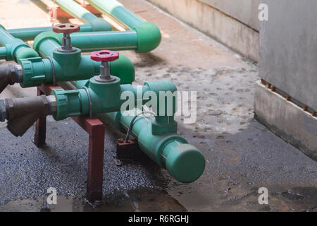 Les tuyaux d'eau vert d'eau et vannes sont sur le sol en ciment, avec de l'eau. Banque D'Images