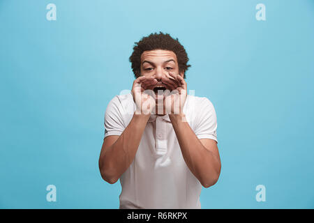 Isolé sur blue young casual man shouting at studio Banque D'Images