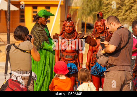 Les touristes prennent des photos de deux femme Himba dans les rues d'Opuwo ville, le nord de la Namibie Banque D'Images