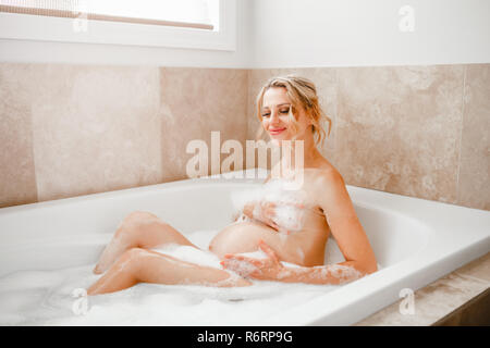 Bonne grossesse en santé. Portrait de femme enceinte libre lave dans la salle de bains. Belle maman attendait dame prendre matin baignoire avec une mousse Banque D'Images