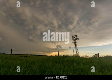 Nebraska moulin avec awesome mammatus nuages à coucher du soleil. Belle silhouette d'un moulin à vent des steppes typiques contre le ciel d'orage. Banque D'Images