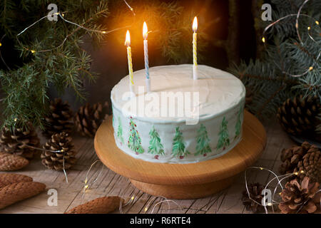 Gâteau de célébration décorées de sapins de Noël sur un fond sombre de branches et de cônes. Style rustique. Banque D'Images