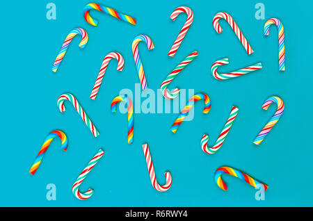 Art fond de Noël avec des bonbons bonbons multicolores Santa's baguettes sur un fond bleu, maison de concept. Mise à plat. Copier l'espace. Banque D'Images