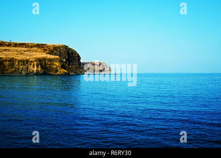 Rocky Mountain grand sec avec de l'herbe d'automne sur la toile de fond de la mer. Sur le littoral et dans l'eau bleu vif. Un rocher se reflète sur la surface de la Banque D'Images