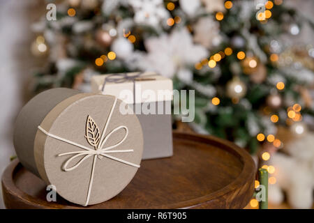 Deux boîtes de fête en papier beige blanc décoré de flocons cordeau de lin sur table en bois.Carte de souhaits.les cadeaux de Noël dans un emballage kraft sur l'arrière-plan d'une guirlande. Nouveau concept de l'année. Maison de concept. Banque D'Images