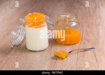 Des yaourts faits maison et de la confiture de pêches sur la table en bois dans un bocal en verre Banque D'Images