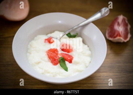 Bouillie bouillie sucrée de semoule dans une assiette avec des tranches de pamplemousse rouge Banque D'Images