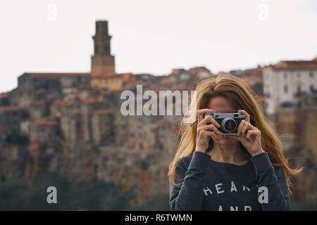 Fille avec appareil photo rétro parlant à l'extérieur, l'Italie, Pitigliano. Toscane Banque D'Images