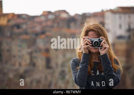 Fille avec appareil photo rétro parlant à l'extérieur, l'Italie, Pitigliano. Toscane Banque D'Images