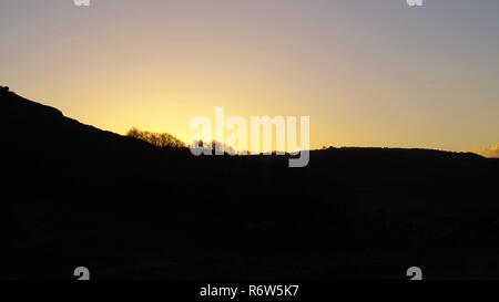 Or d'un coucher de soleil d'hiver, la vallée Silhouetting haut contre un ciel clair. Vallée des Roches, Exmoor National Park, North Devon, UK. Banque D'Images