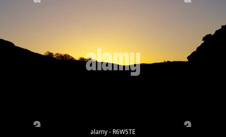 Or d'un coucher de soleil d'hiver, la vallée Silhouetting haut contre un ciel clair. Vallée des Roches, Exmoor National Park, North Devon, UK. Banque D'Images