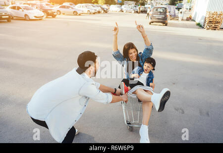 Jeune maman et papa porte fils dans un panier sur le parking Banque D'Images