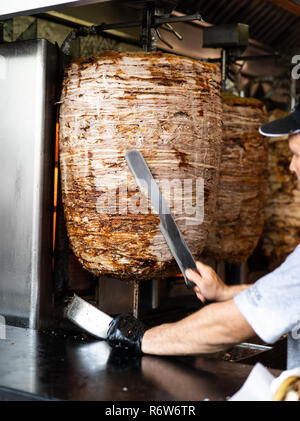 Man's hands holding un couteau de coupe, les coupes d'une brochette verticale Banque D'Images