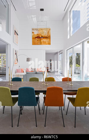 Chaises multicolores à chaise de salle à manger à table dans un espace ouvert en hauteur double villa de nouvelle construction, Quinta do Lago Banque D'Images