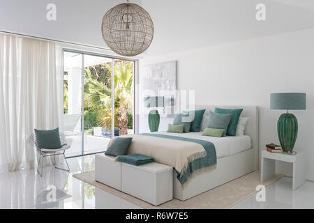 Couvertures et coussins vert avec de grandes lampes de chevet et ouvrir la porte de jardin dans villa de nouvelle construction, Quinta do Lago Banque D'Images