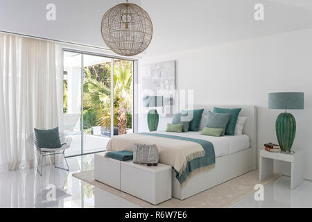 Couvertures et coussins vert avec de grandes lampes de chevet et ouvrir la porte de jardin dans villa de nouvelle construction, Quinta do Lago Banque D'Images