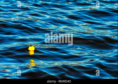 Pêche jaune flottante bobber et bobby sur le déménagement d'un lac d'eau bleu Banque D'Images