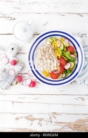 Gruau d'avoine avec légumes salade composée de tomates, maïs, concombres et laitue. La lumière, sain et savoureux petit-déjeuner diététique. Vue d'en haut Banque D'Images