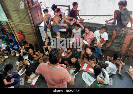 Travailleur social de la Kuya Centre pour enfants de la rue sont en contact avec les enfants sans-abri à s'inscrire sur un marché à Quezon City, Metro Manila, Philippines Banque D'Images