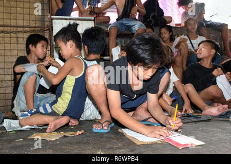 Travailleur social de la Kuya Centre pour enfants de la rue sont en contact avec les enfants sans-abri à s'inscrire sur un marché à Quezon City, Metro Manila, Philippines Banque D'Images