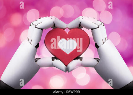 Close-up of a Robotic Hand Holding Red Heart Banque D'Images