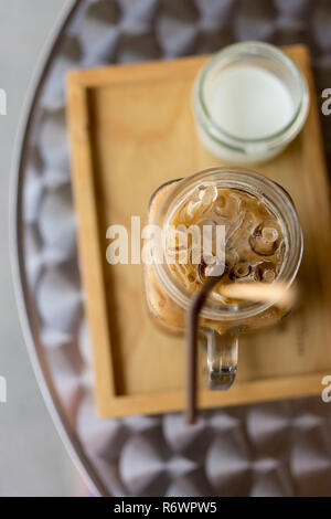 Café glacé Thai avec du lait dans un verre pot Mason sur plateau en bois et dessus de table, la profondeur de champ. Banque D'Images