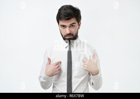 Beau froncer espagnol homme avec barbe et cheveux volumineux pointant du doigt en lui-même Banque D'Images