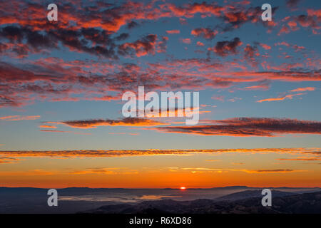 Coucher de soleil spectaculaire avec des nuages rouges sur un fond de ciel bleu ; baie de San Francisco, Californie Banque D'Images