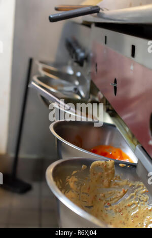 La face avant de grill et de télévision commerciale haut appareil dans une cuisine commerciale. Bol en acier inoxydable avec des sauces et des pinces à utiliser ainsi. Banque D'Images